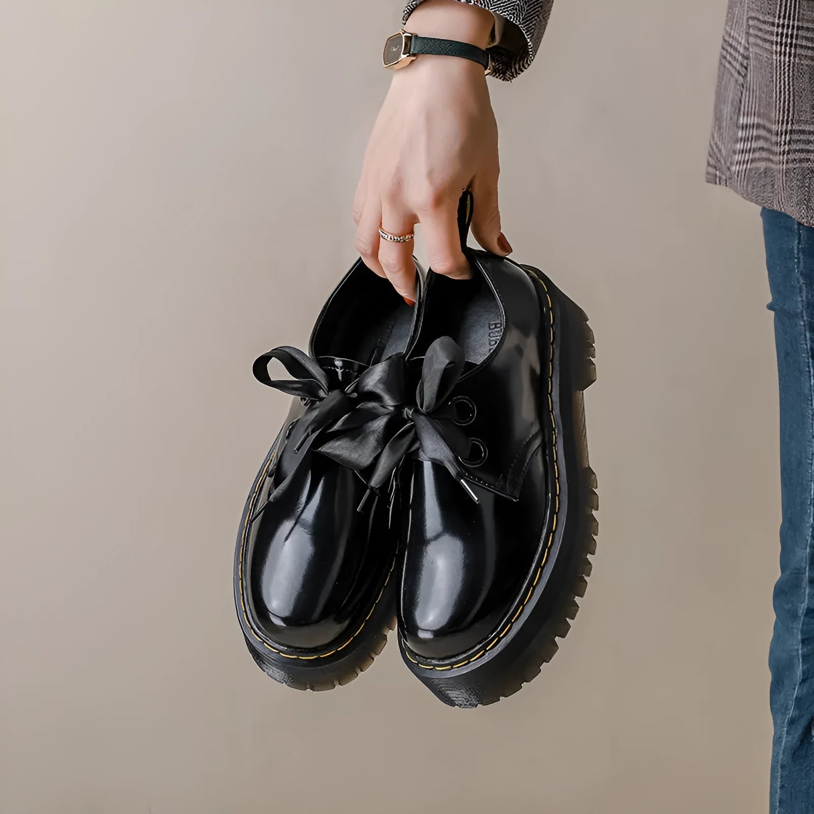Black women's thick soled lace-up shoes with a cross-strap and ribbon detail on the front.