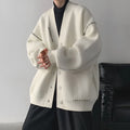 Women's loose-fit knitted cardigan coat in black or white, showing long sleeves and solid colour.