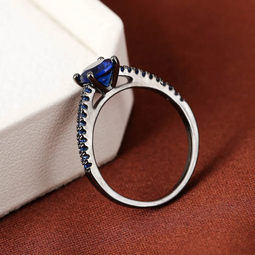 A geometric hexagon-shaped copper ring in a gun black and purple electroplated finish, shown from the side.