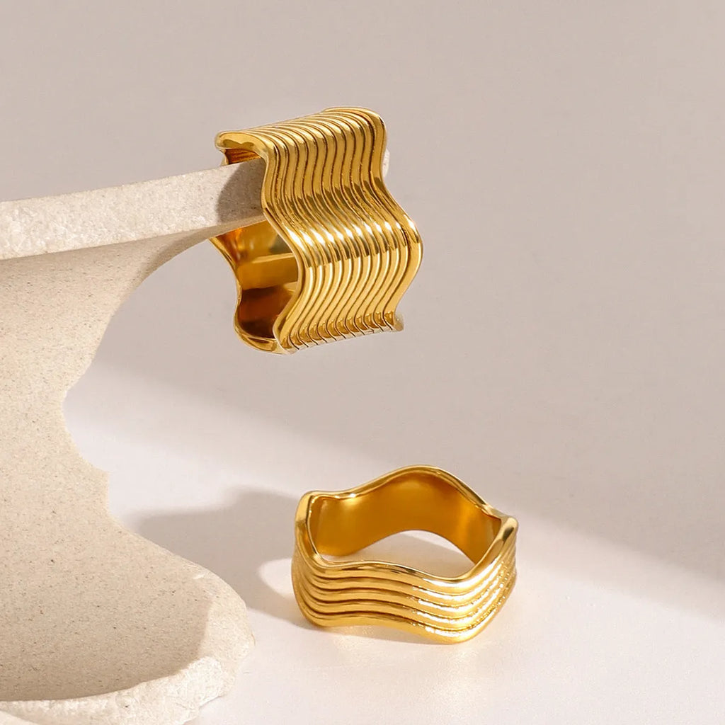 Stainless steel women's ring with wide geometric wave pattern in silver or gold tone.