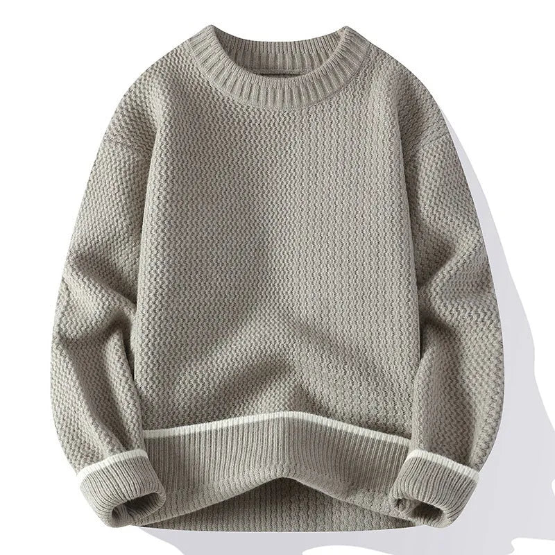 Man wearing a grey loose-fit round neck long sleeve pullover sweater.