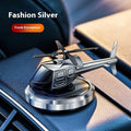 Silver metal solar-powered helicopter car air freshener clipped to a vehicle air vent, with rotating blades.