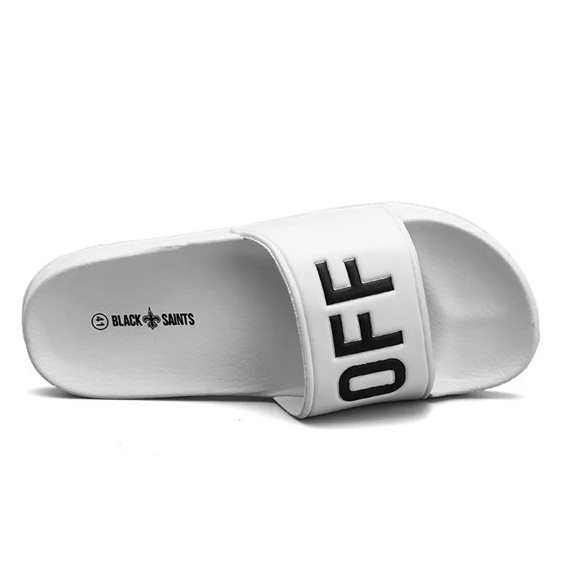 Men's black open-toe slipper with textured rubber sole, shown on a wooden floor.