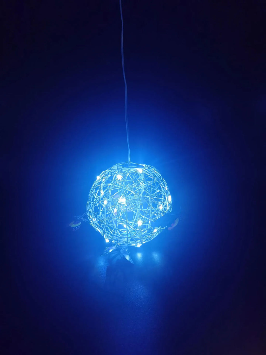 White outdoor solar ball light with random colour butterfly decorations on a garden lawn