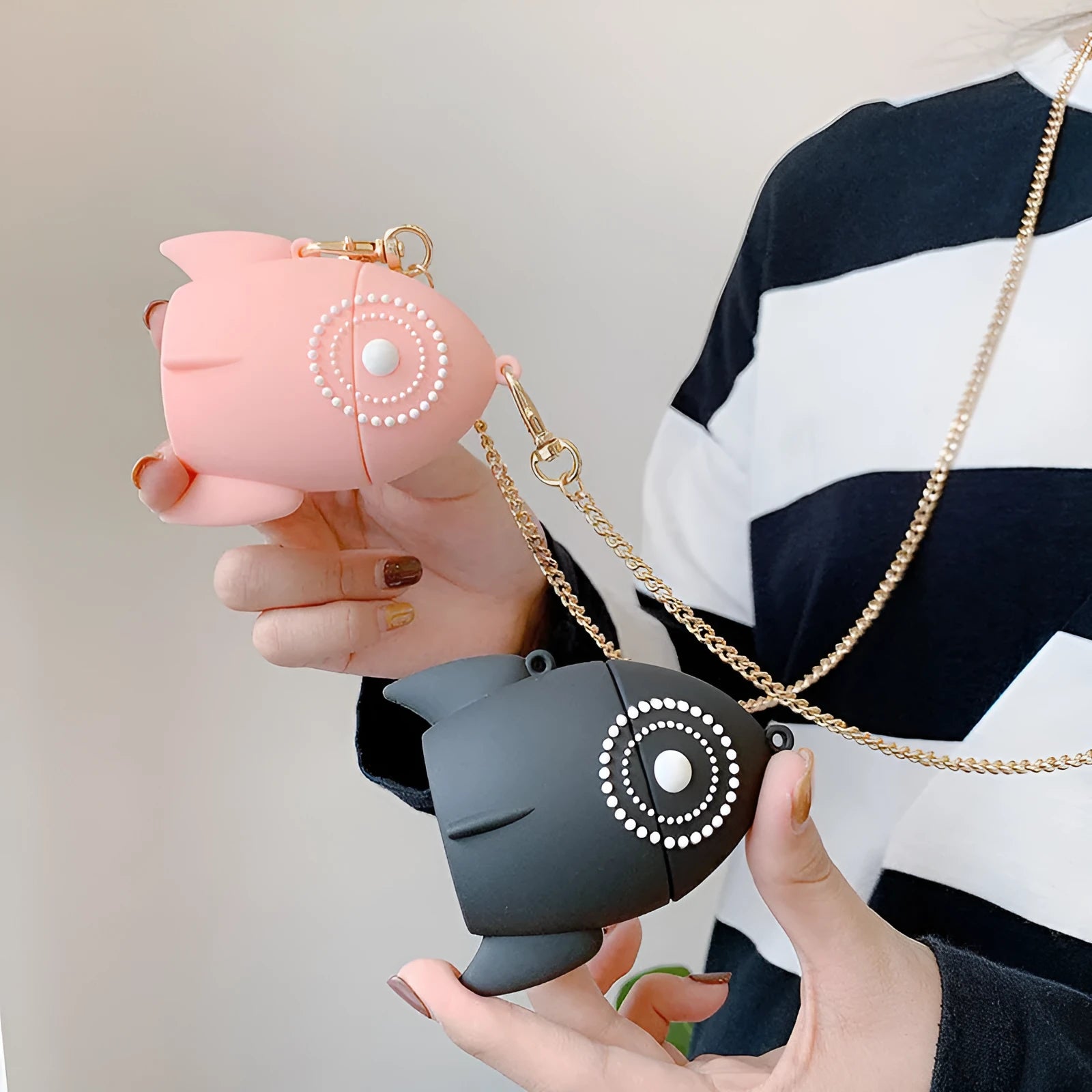 Pink silicone AirPods case with raised rocket design next to black plain version