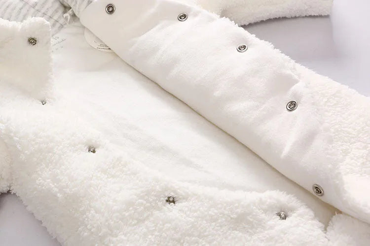Baby wearing a cotton padded winter jumpsuit with long sleeves, available in marrón, pink, or white colours.