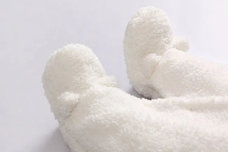 Baby wearing a cotton padded winter jumpsuit with long sleeves, available in marrón, pink, or white colours.