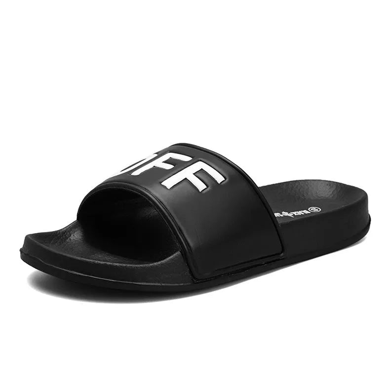 Men's black open-toe slipper with textured rubber sole, shown on a wooden floor.