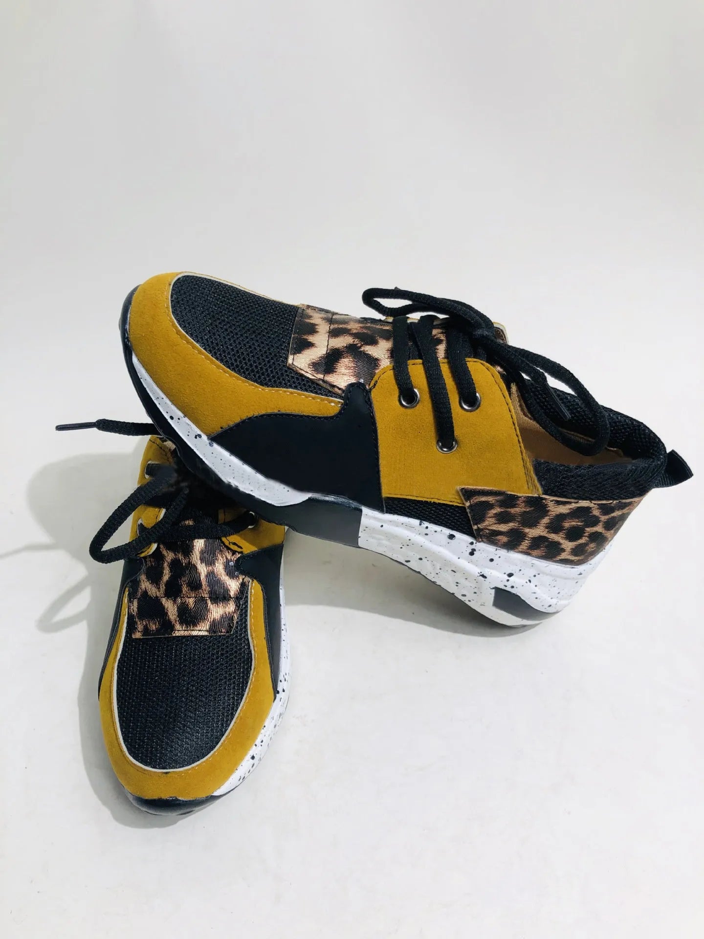 Women's black suede wedge sneakers with a low-cut ankle and round toe on a wooden floor.