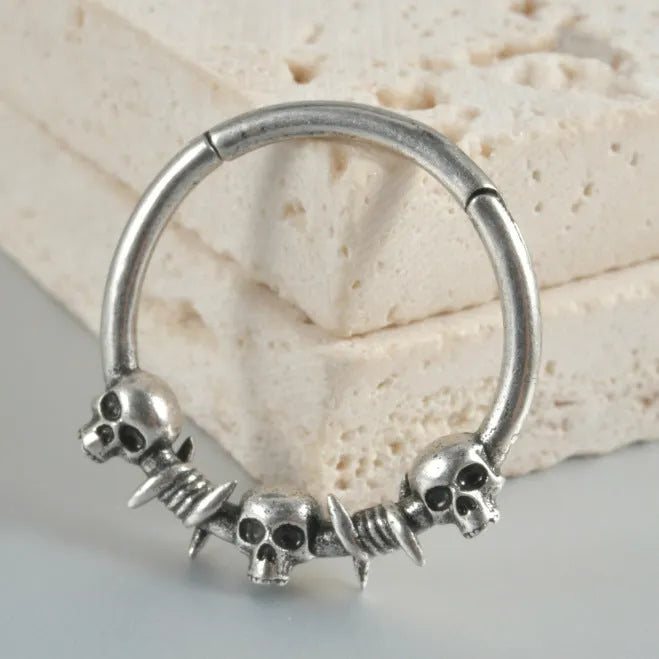 A pair of vintage-style copper earrings with an embossed ghost head design on a stud post, showing an antique silver finish.