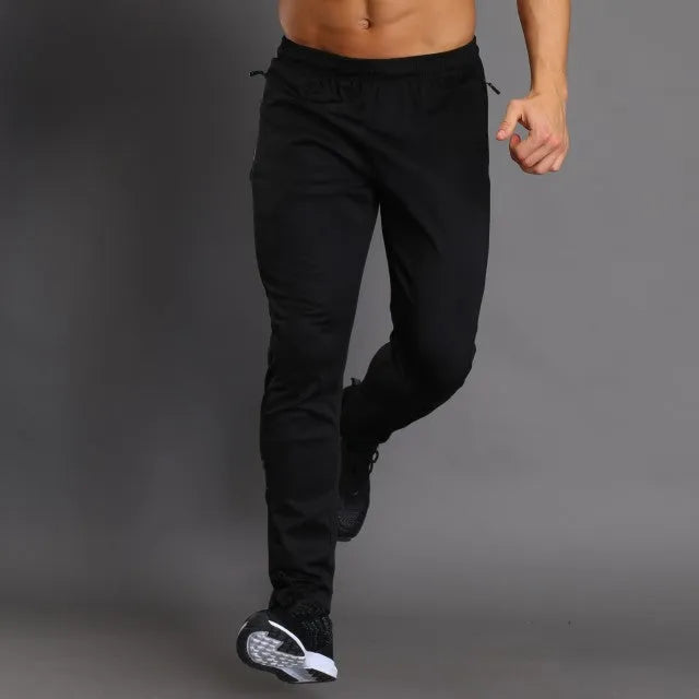 Black slim-fit running fitness trousers with reflective printing and zipper pockets on a model