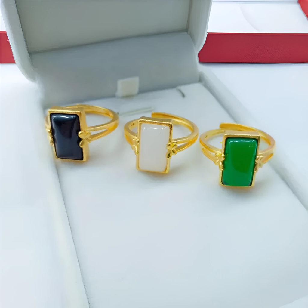 Close-up of an adjustable brass gold-plated ring with an electroplated finish and a green artificial gemstone inlay.