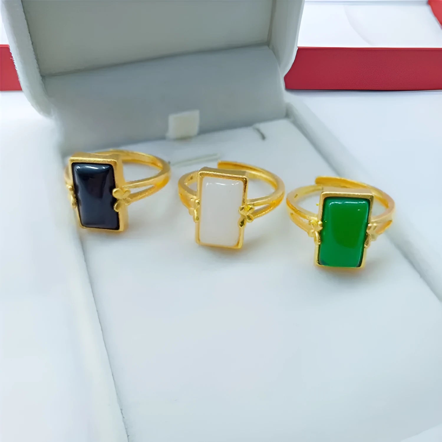 Close-up of an adjustable brass gold-plated ring with an electroplated finish and a green artificial gemstone inlay.