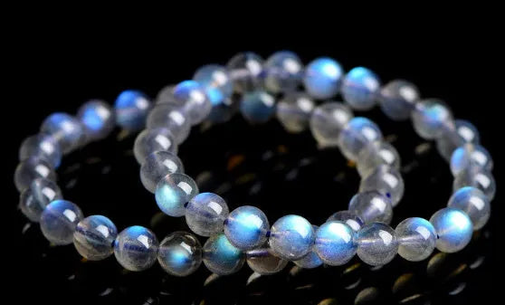 Polished natural cream body blue moonlight crystal bracelet on a wrist, showing simple bead design.