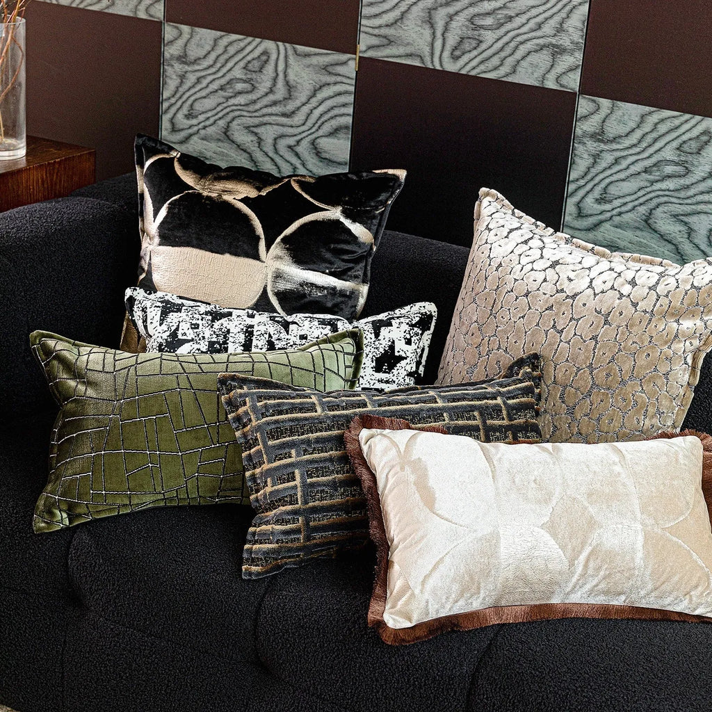 Black and gold abstract pattern decorative square and waist pillow cushions on a grey sofa.