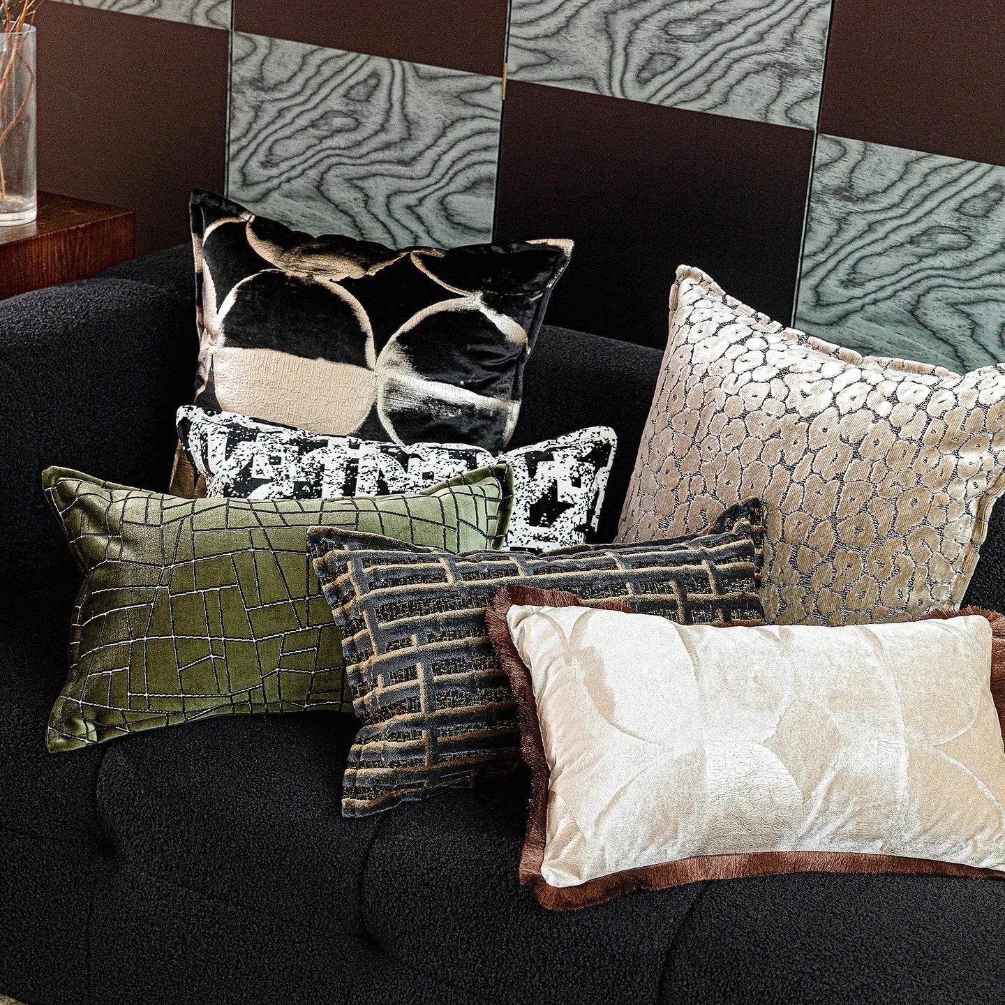 Black and gold abstract pattern decorative square and waist pillow cushions on a grey sofa.