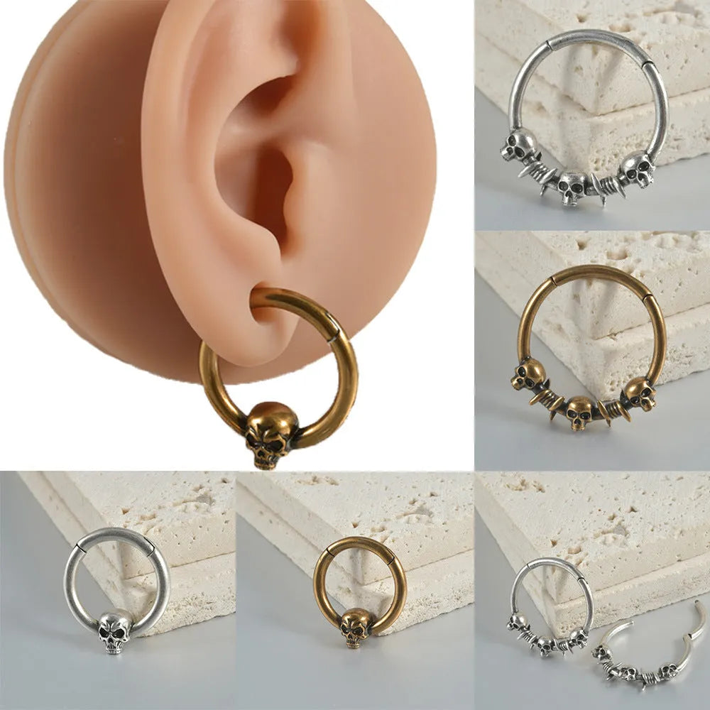 A pair of vintage-style copper earrings with an embossed ghost head design on a stud post, showing an antique silver finish.