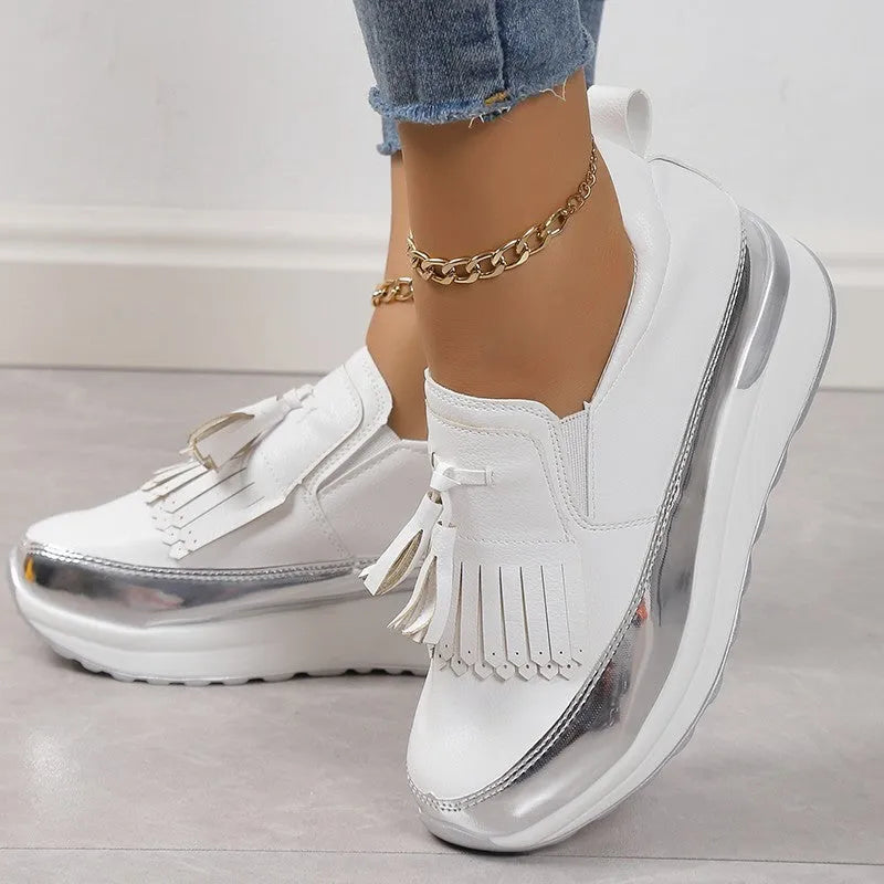 Women's black casual platform shoes with tassel decoration and a distinctive English muffin wedge heel.