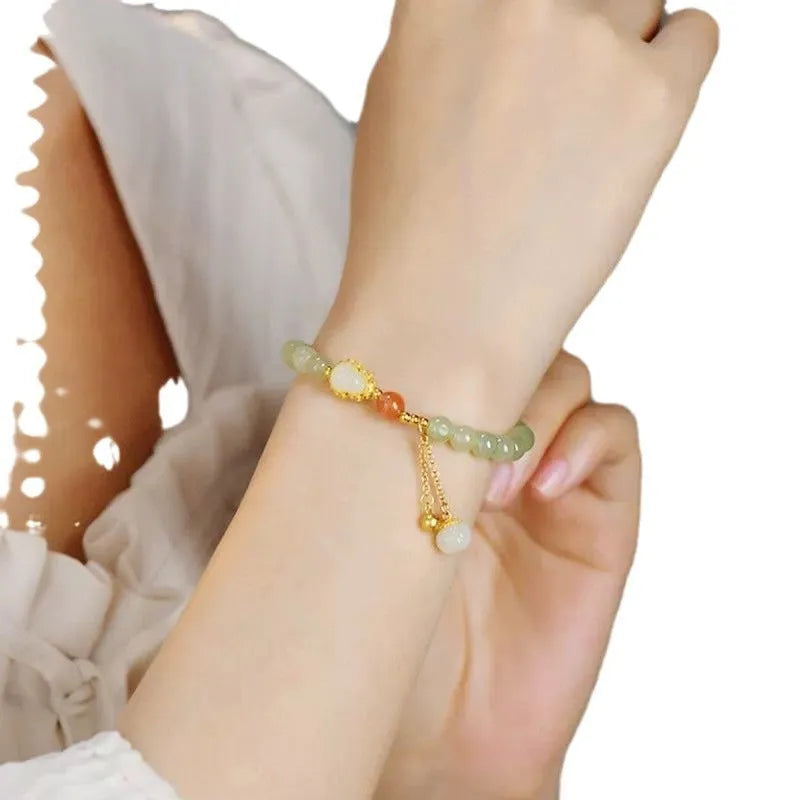 Qingshui jade women's bracelet with gold plated beads and a fu character charm.