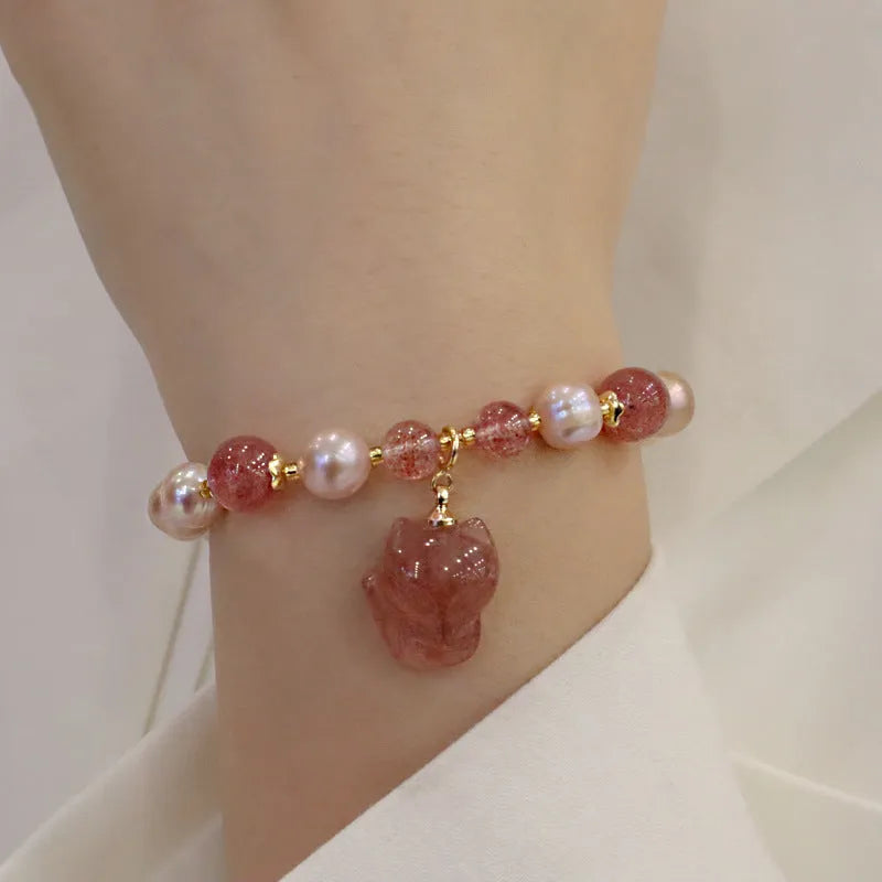 Women's light pink freshwater pearl and strawberry quartz bracelet with a silver fox charm on an adjustable chain.
