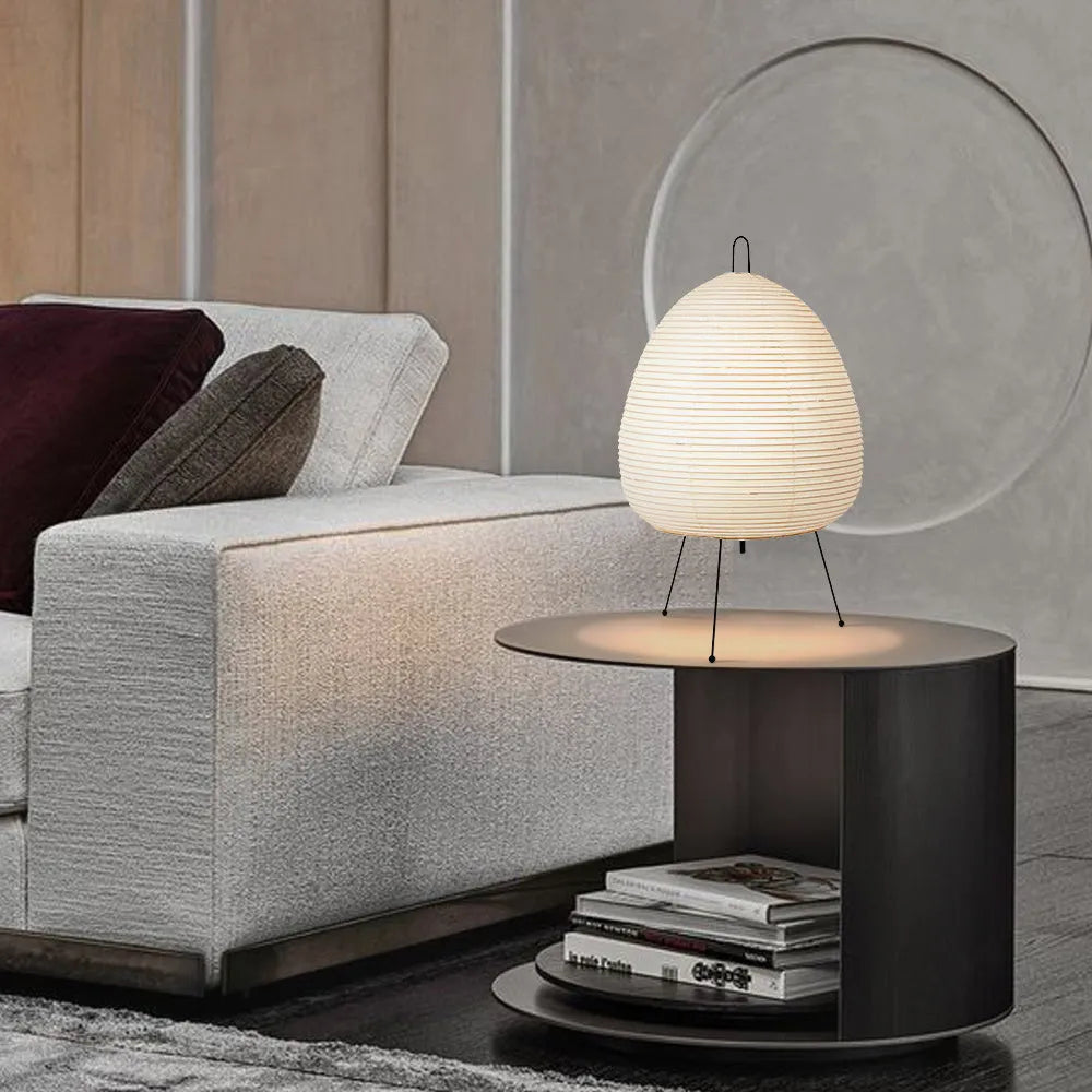 Japanese style table lamp with a white handmade rice paper lantern shade and aluminium base on a wooden table.