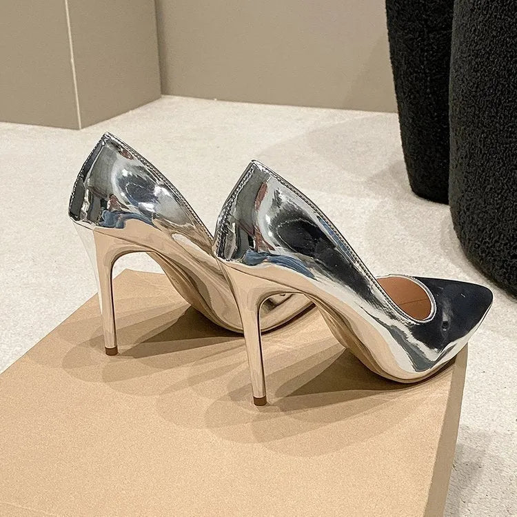 Gold and silver pointed toe stiletto heel slip-on pumps on a plain background