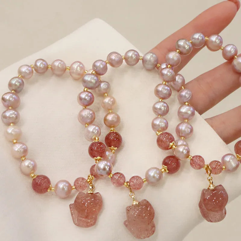 Women's light pink freshwater pearl and strawberry quartz bracelet with a silver fox charm on an adjustable chain.