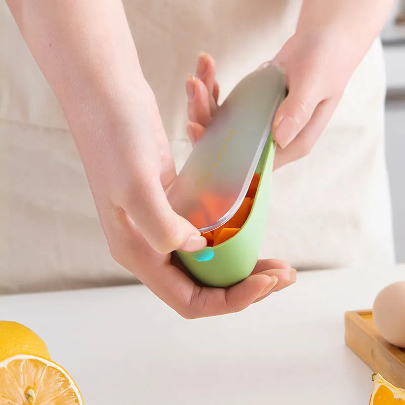 Dark green kitchen peeler with plastic handle inside its clear storage tube on a wooden surface.