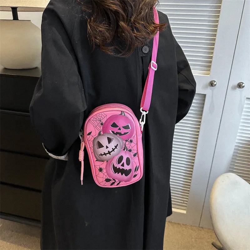 Black Halloween crossbody bag with orange pumpkin, white ghost, and black bat graffiti print, shown on adjustable strap.