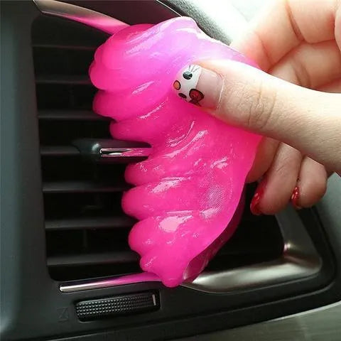 Blue magic cleaning gel putty being pressed onto a laptop keyboard to remove dust.