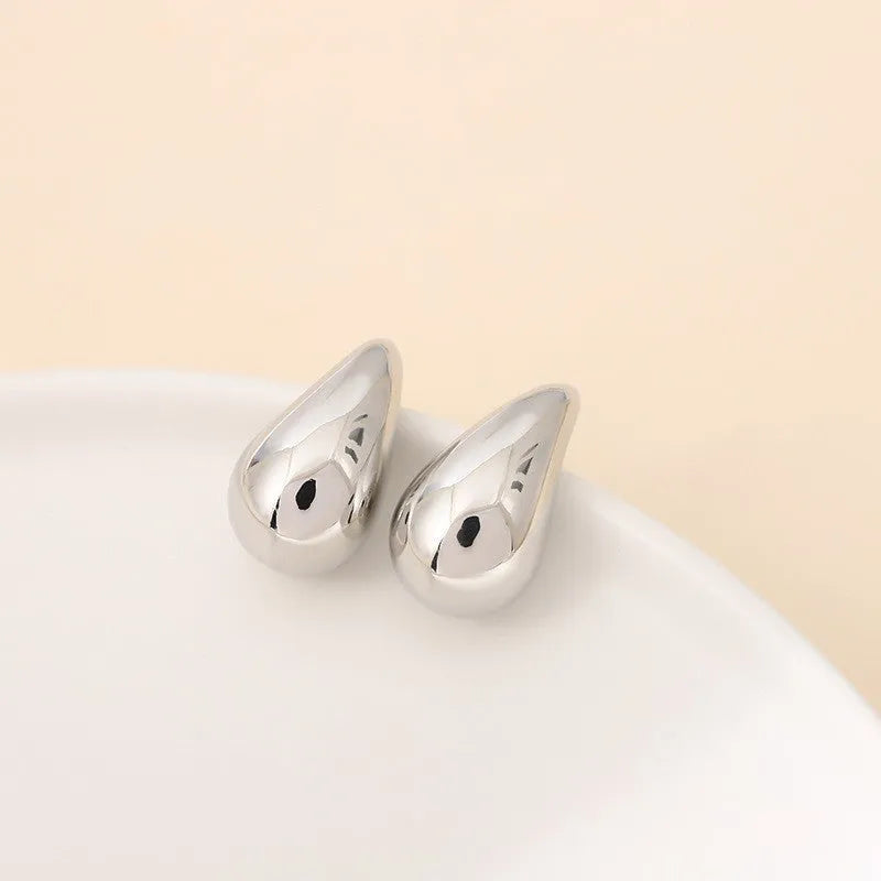 Minimalistic water drops earrings in gold plated copper, drop shape stud style on white background