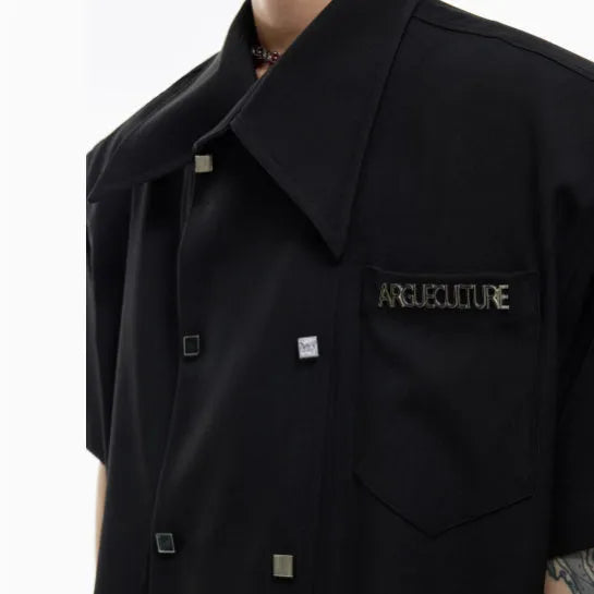 A man's loose-fitting short-sleeved casual shirt in a choice of black, blue, or white, showing lapel collar and metal decoration details.