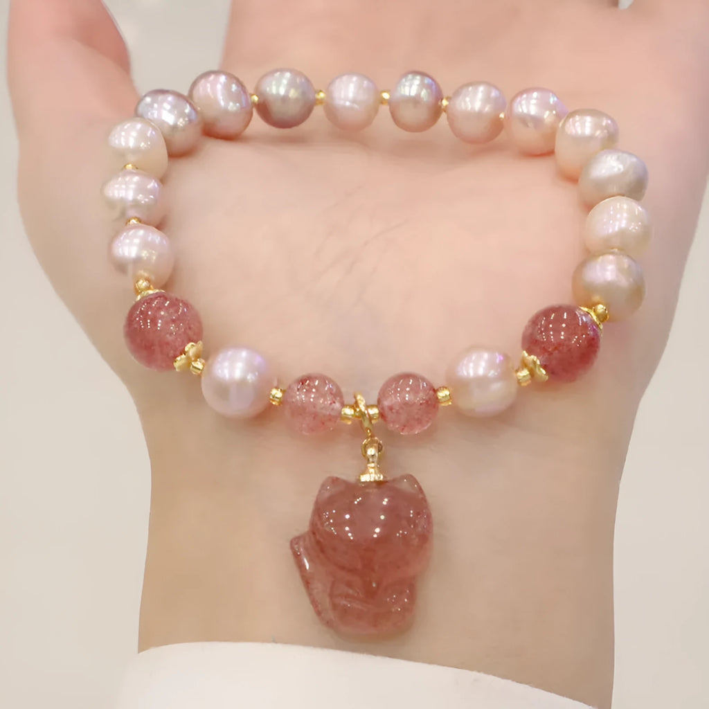 Women's light pink freshwater pearl and strawberry quartz bracelet with a silver fox charm on an adjustable chain.