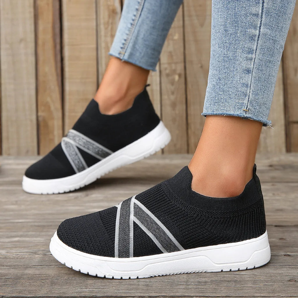 Black women's flat casual shoes with flyknit mesh upper and tassel detail on a flat rubber sole.