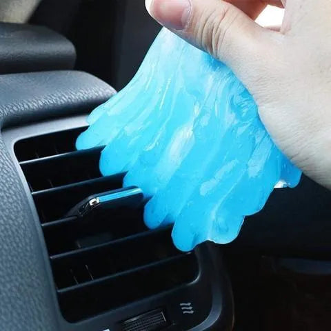Blue magic cleaning gel putty being pressed onto a laptop keyboard to remove dust.