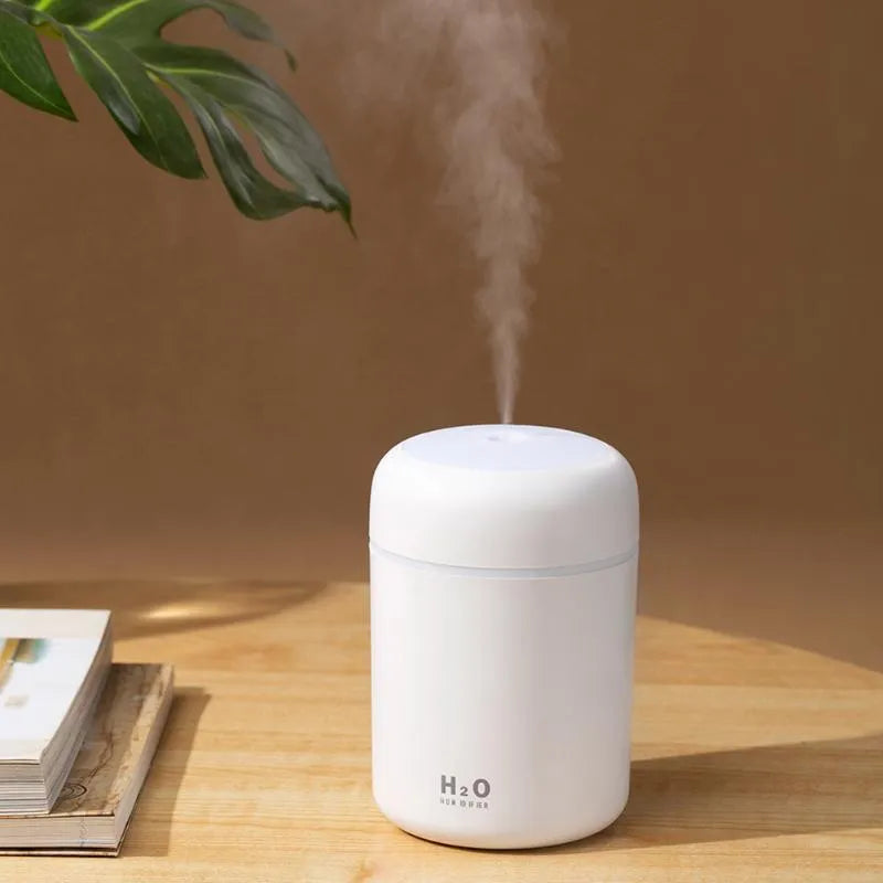 Pink USB desktop humidifier with LED lights and water tank on wooden desk