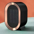 Compact desktop ceramic fan heater in black on a wooden desk.