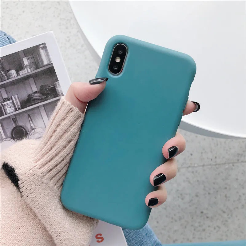 Silicone phone case for iPhone on a table, shown in a choice of eight colours including bean green and rose gold.