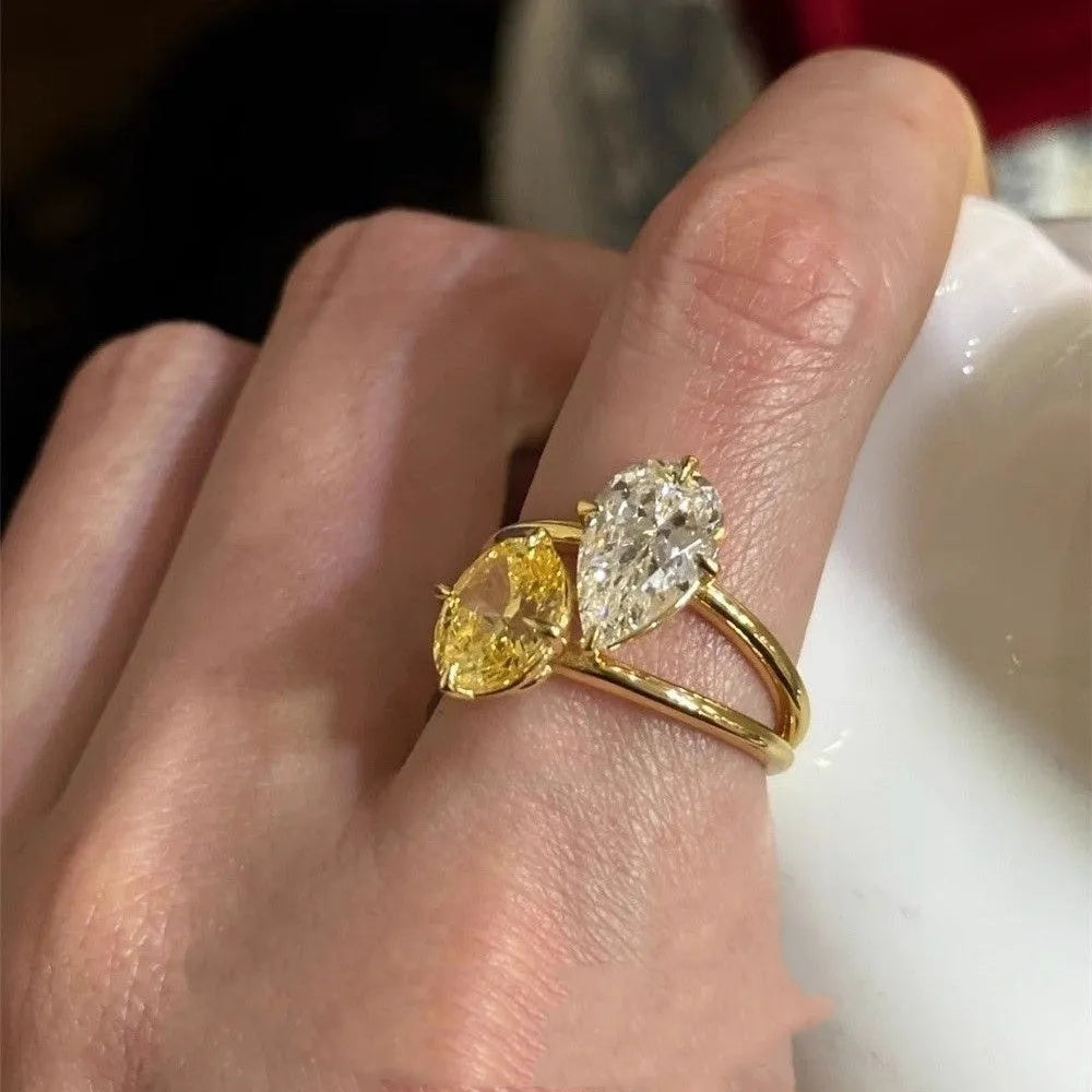 Geometric open-back silver ring with large central pear-cut clear zircon stone on a model's hand.