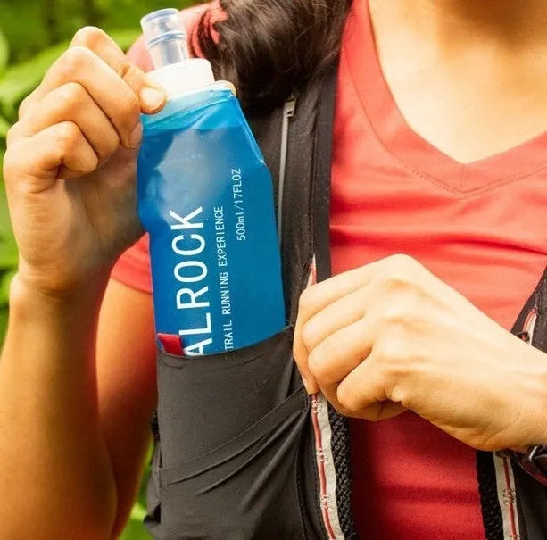 Mountain Cliking portable plastic straw with black clip attached to a green backpack strap
