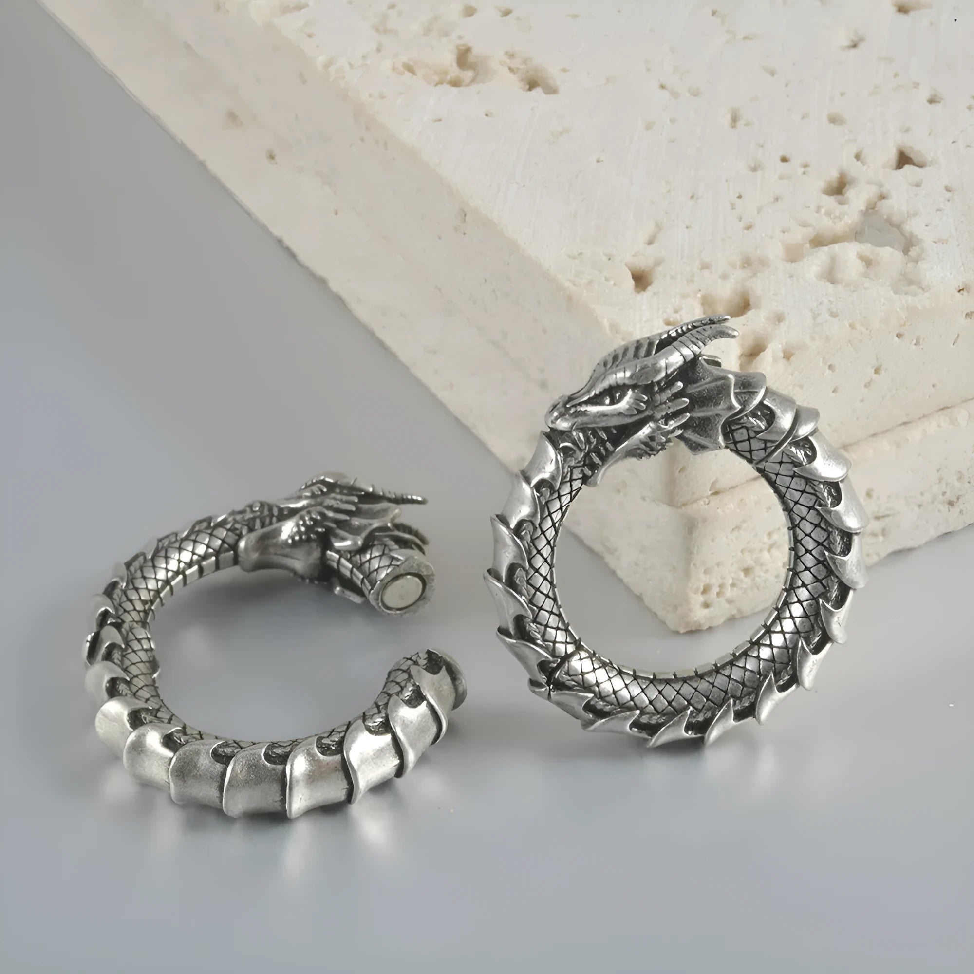 A pair of large, geometric dragon-shaped alloy earrings with an antique silver finish and hollow-out details.