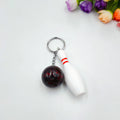Mini bowling pin simulation keychain in blue, red, green, and purple colours on a metal ring.