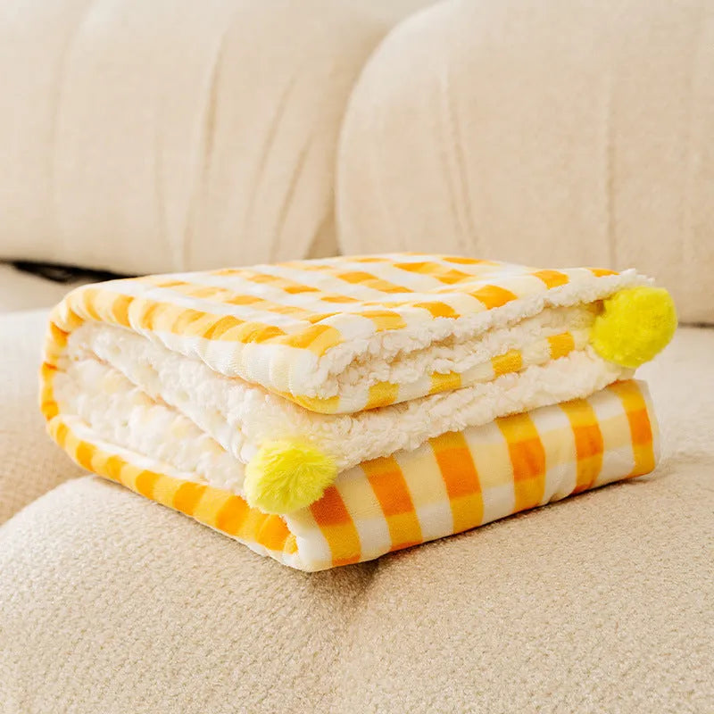 Blue coral fleece pet blanket folded next to a sleeping dog on a sofa.