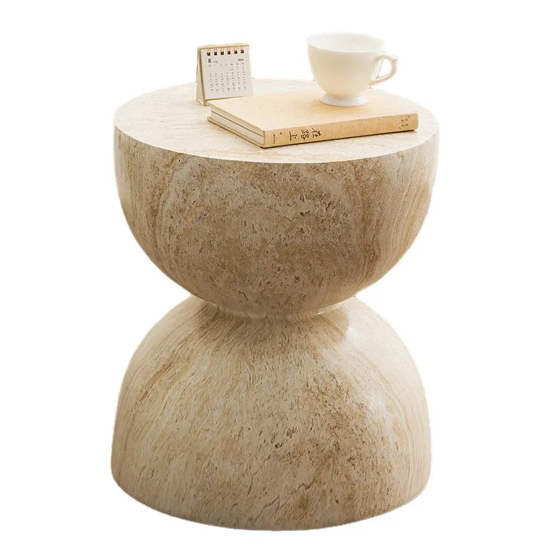 Modern hourglass-shaped tea table in imitation cave stone finish placed beside a sofa in a living room