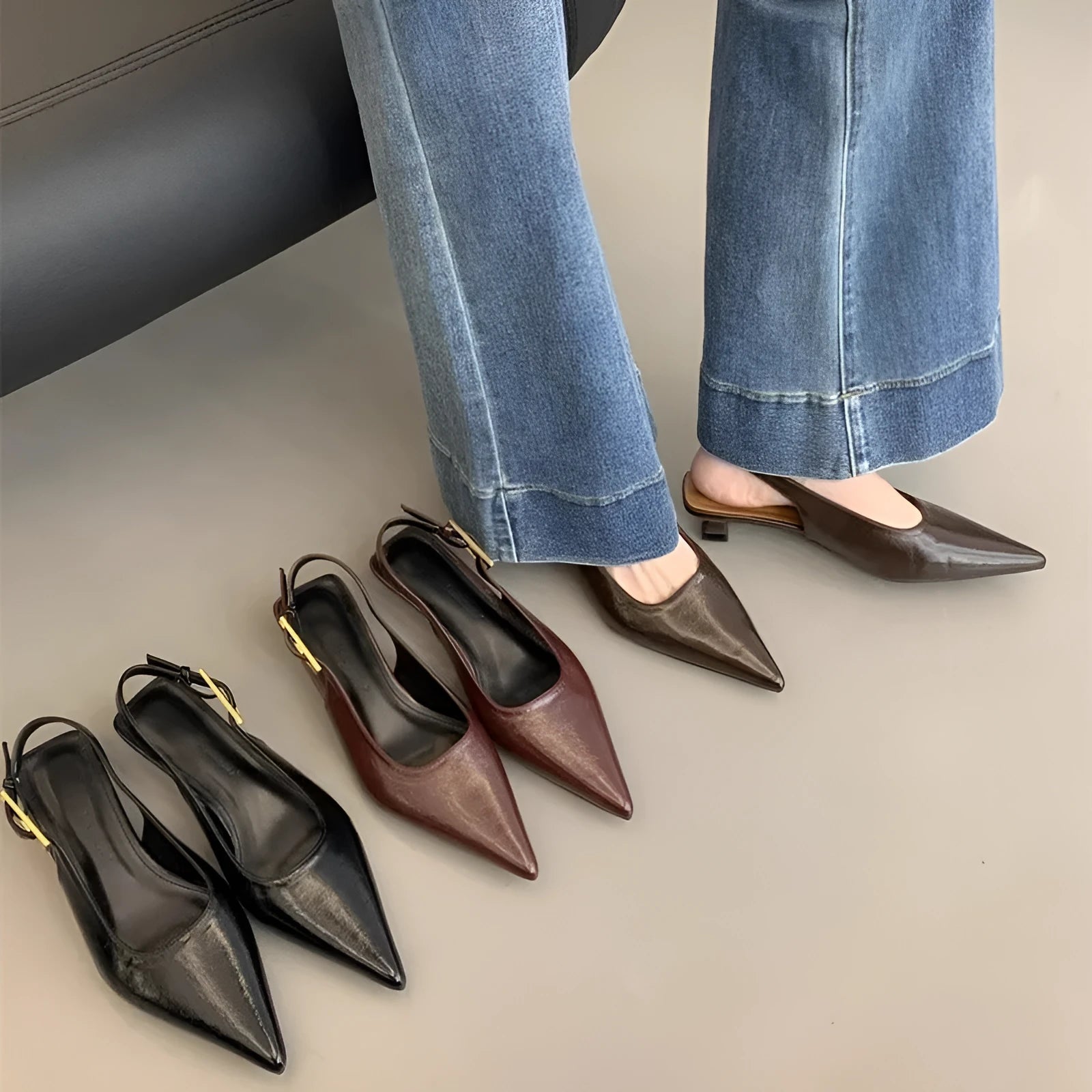 Black leather pointed toe women's shoes with a thin low heel and an ankle strap.
