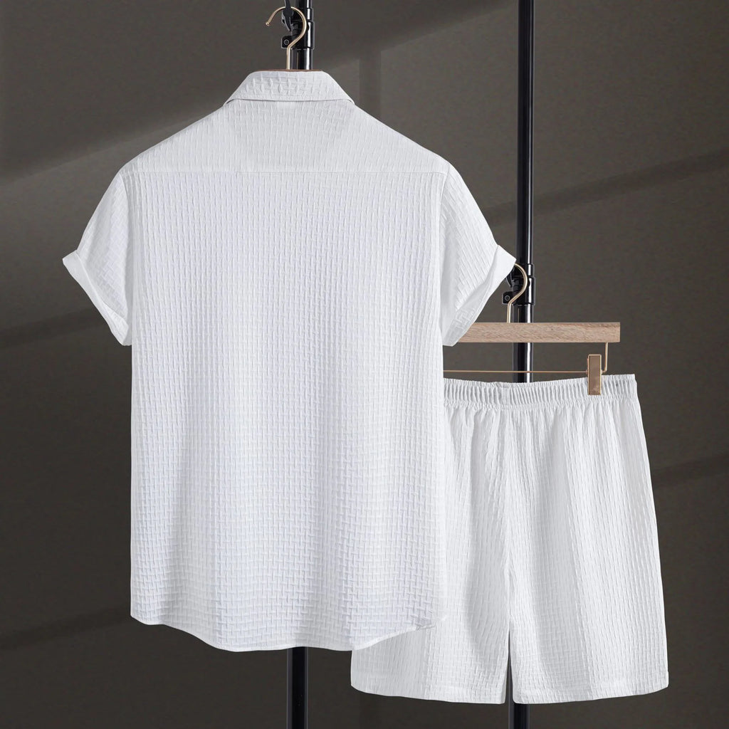 A man wearing a solid colour short-sleeve shirt and matching shorts from a casual beachwear set.