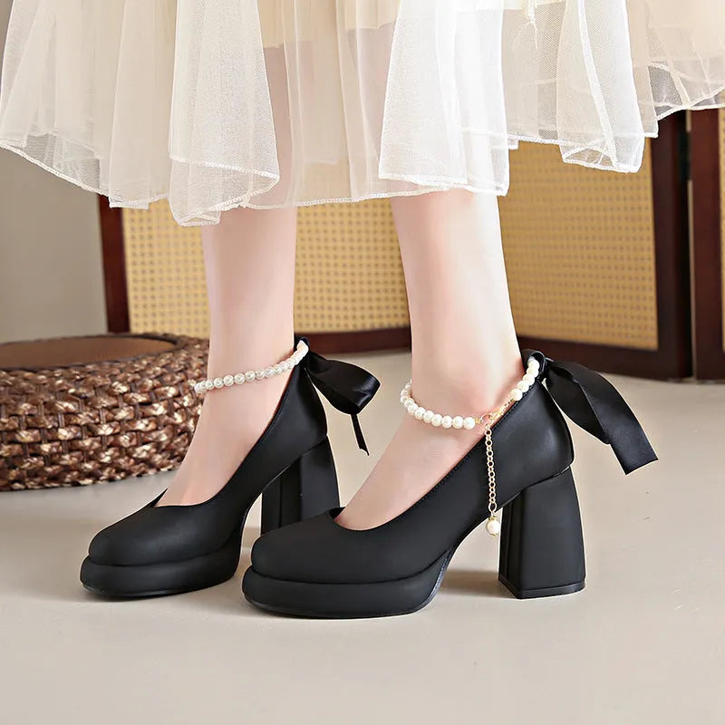 Beige women's Mary Jane shoes with chunky heel, round toe, and pearl- detail ankle strap on a white background.