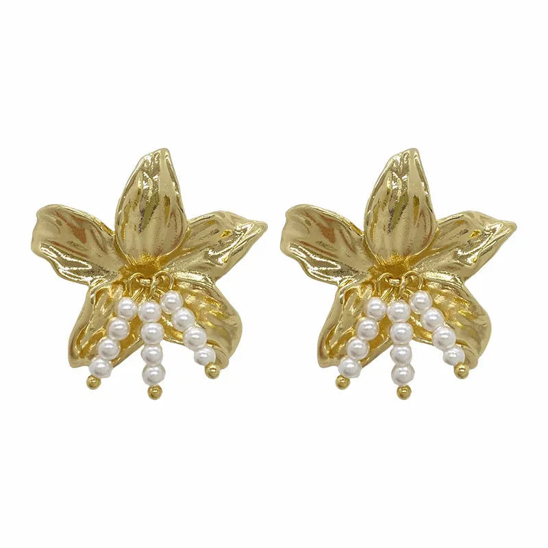 Golden flower-shaped earrings with pearl details on a white background.