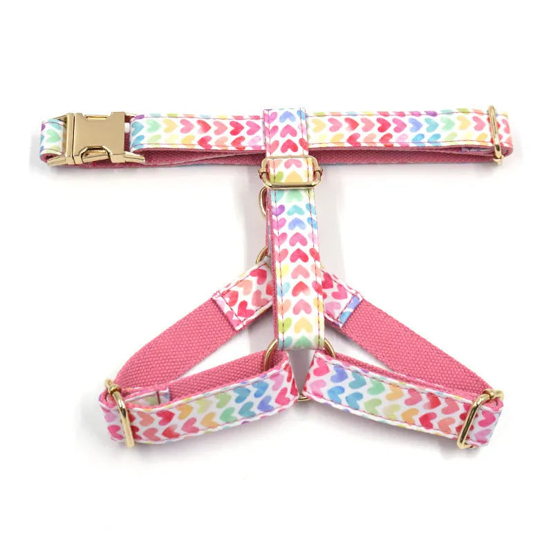 Pink dog harness with gold buckle and heart-shaped stone decoration on white background