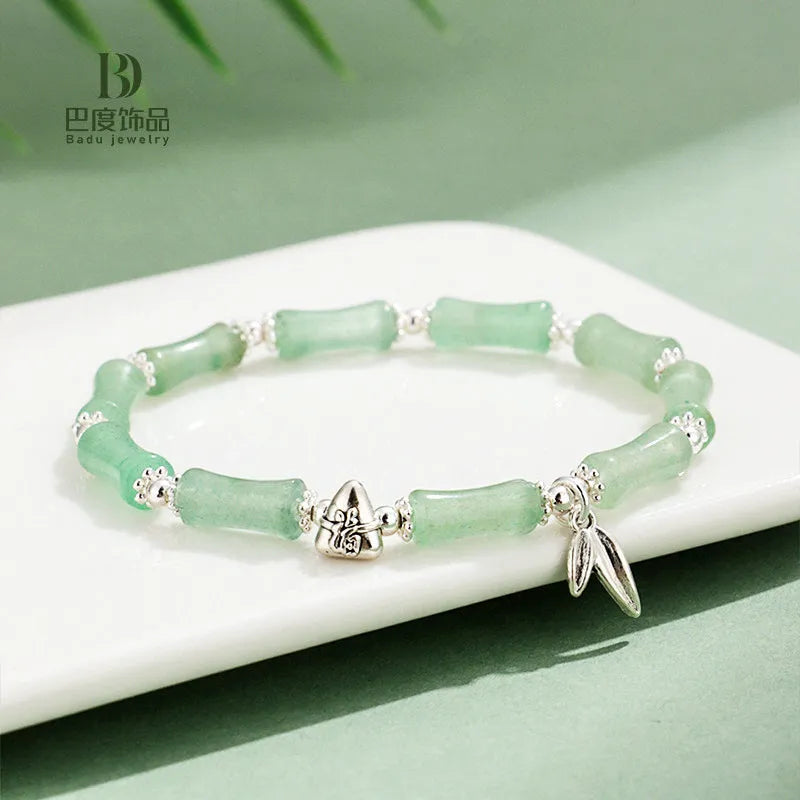 Women's green aventurine crystal bracelet with bamboo, strawberry quartz, and jade beads on wrist.